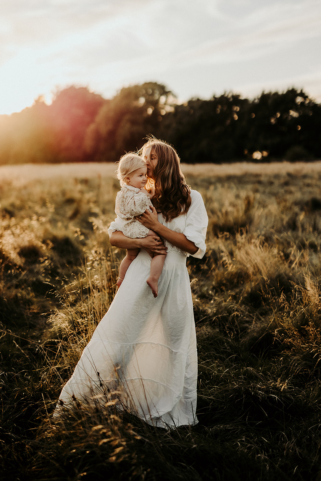 en mamma som håller om sitt barn på ett fält i solnedgången