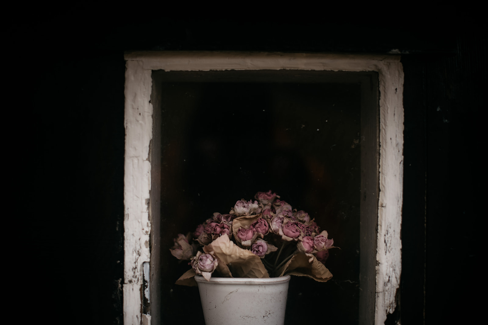 Flower bouquet in small window of a wooden house