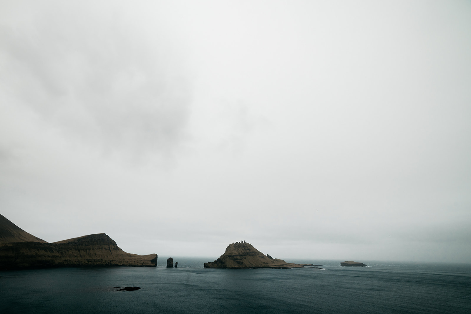 Small islands peaking through dark ocean on cloudy day