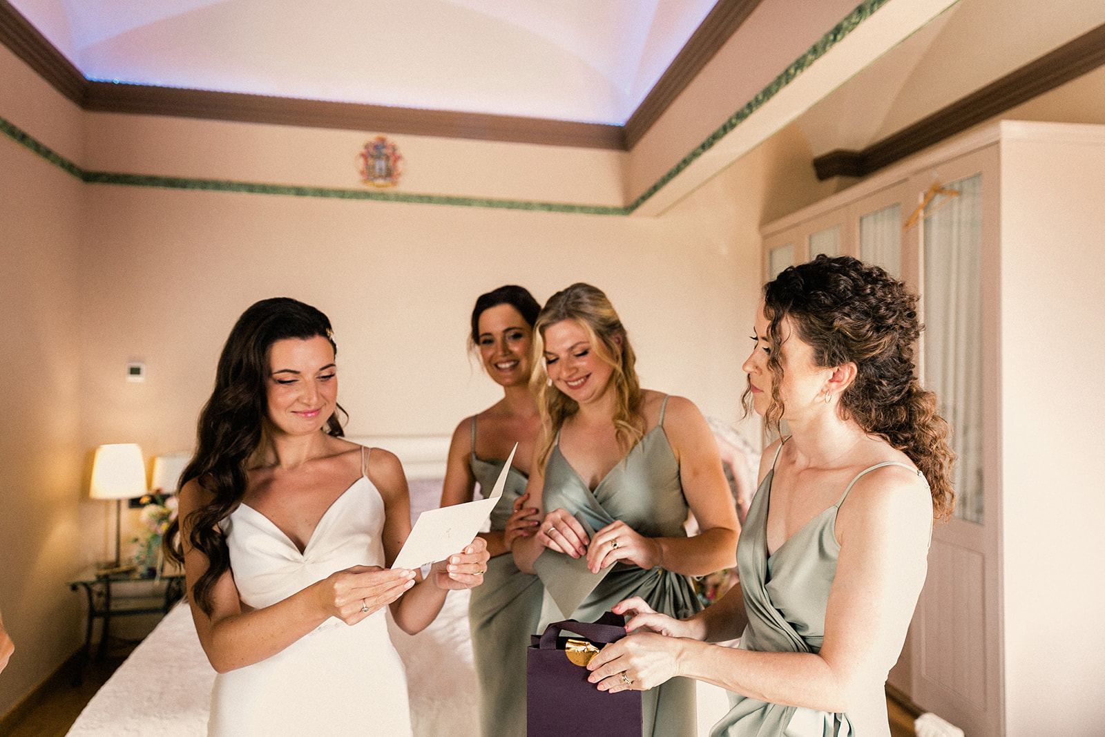 A bride with standing in her wedding dress standing with her brides maids, reading a letter