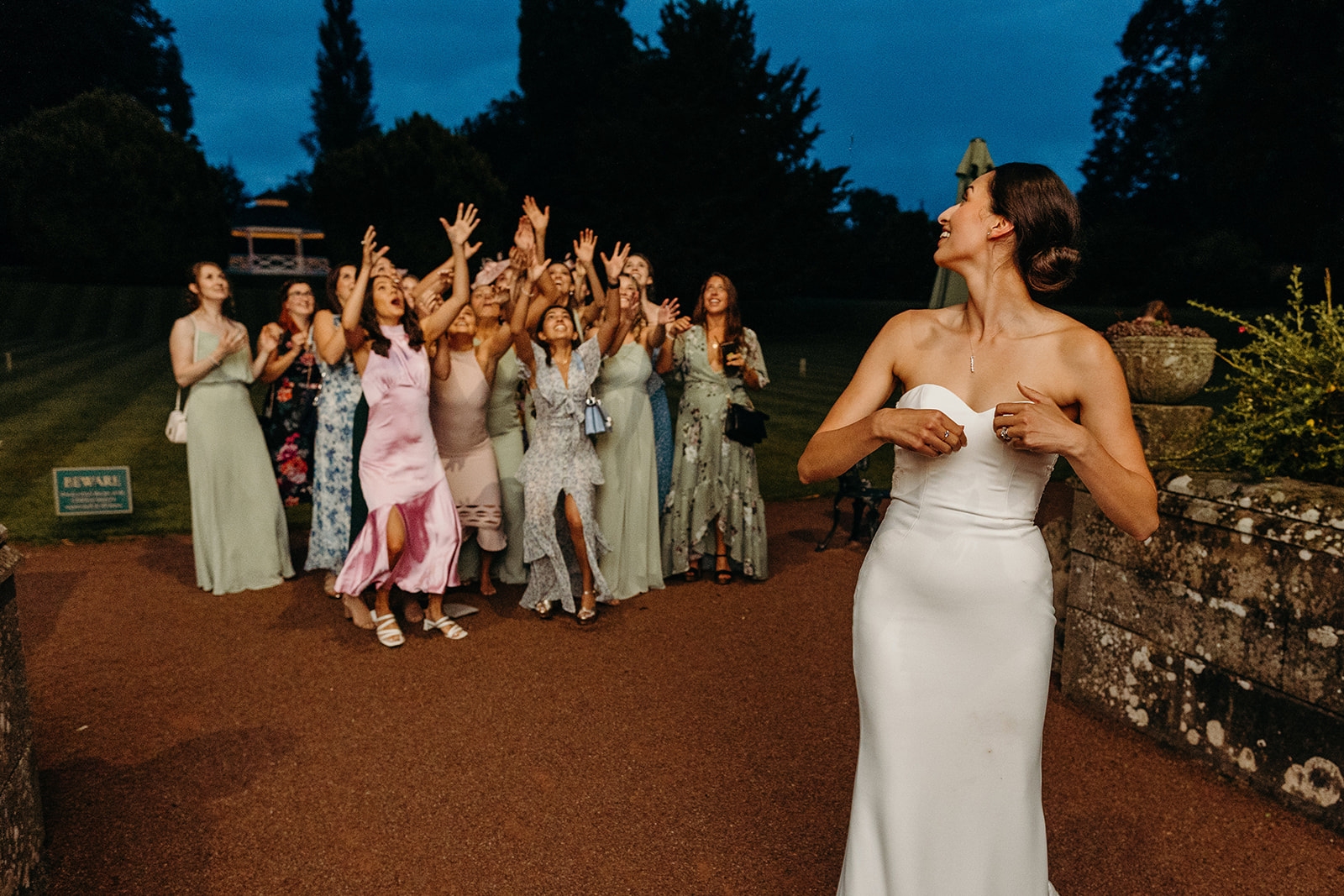bride throwing bouquet with woman trying to catch in distance