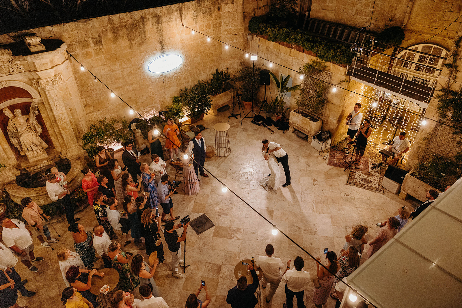 couple first dance in courtyard with guests watching