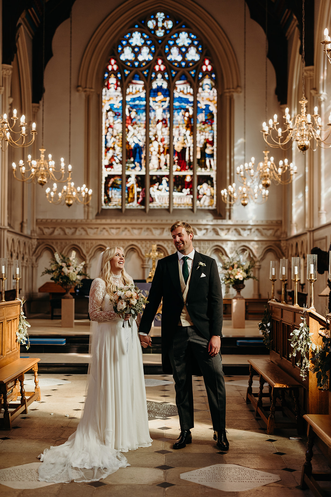 couple post after ceremony in majestic church with stained glass