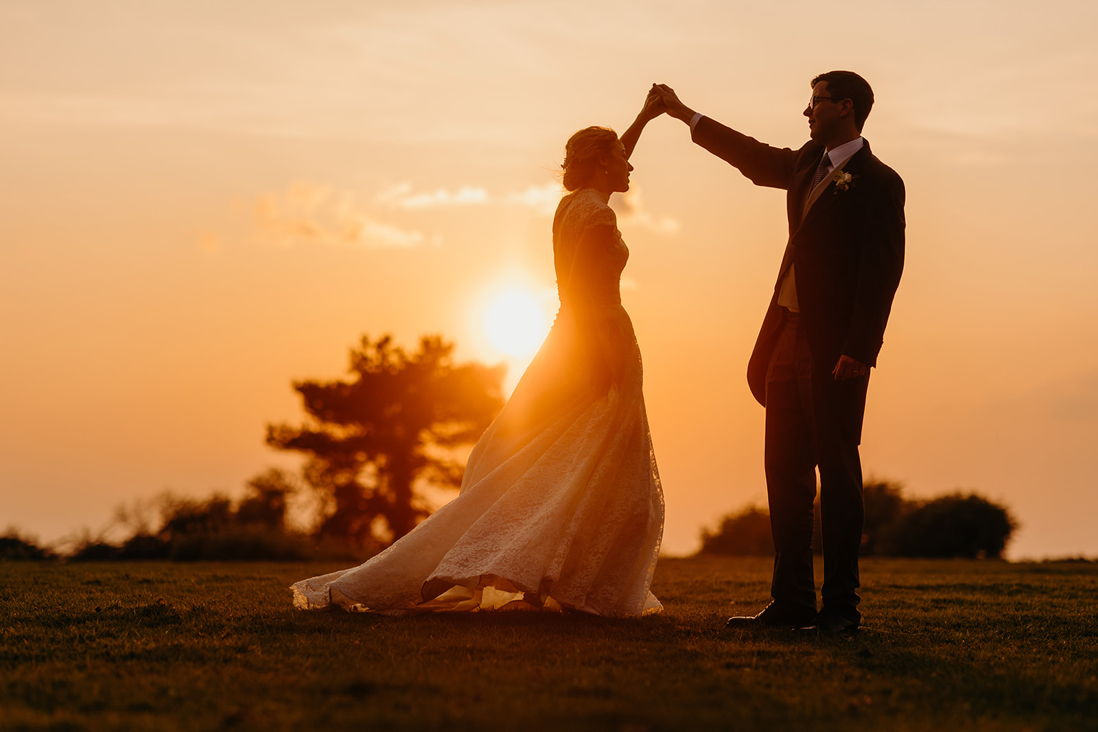 sunset photograph of groom twirling bride