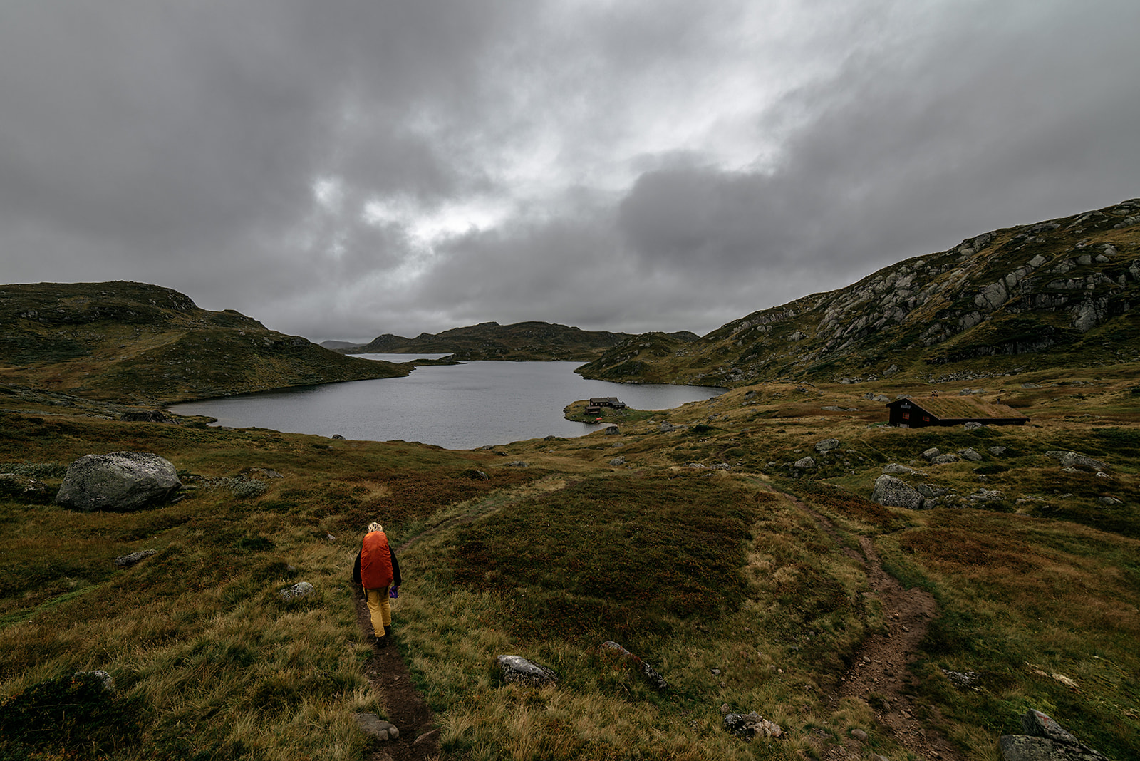 Hiker approaching small cabin at a mountain lake