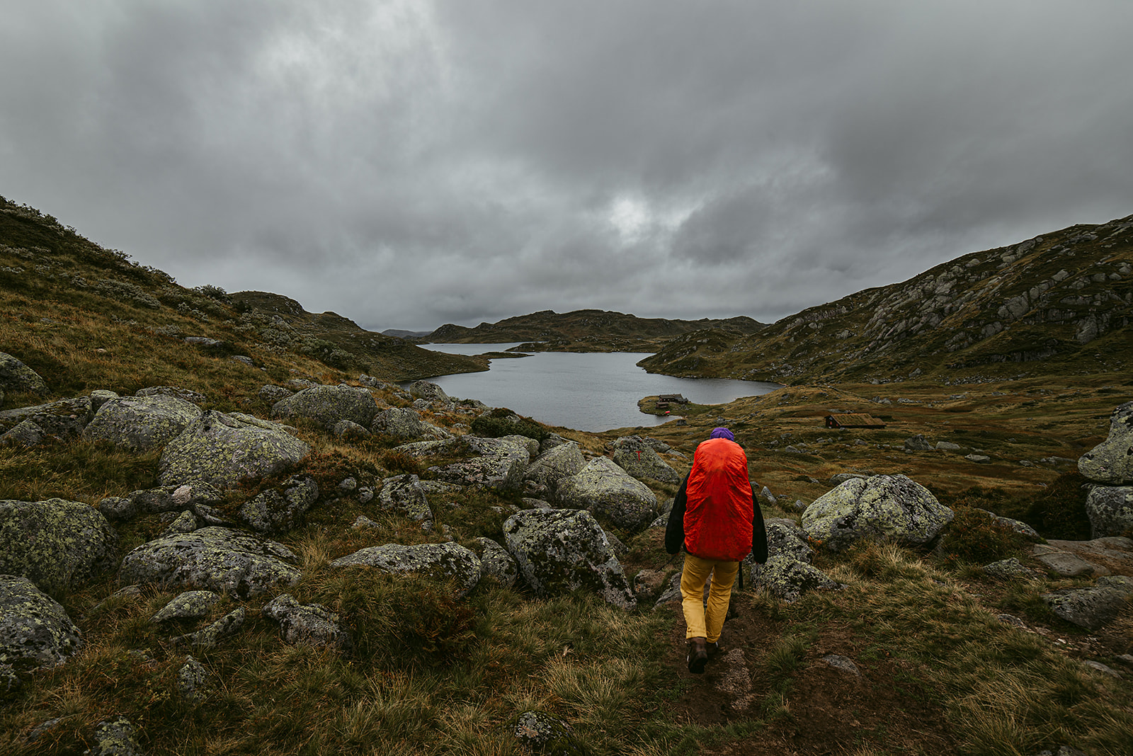 Hiker walking towards a mountain lake
