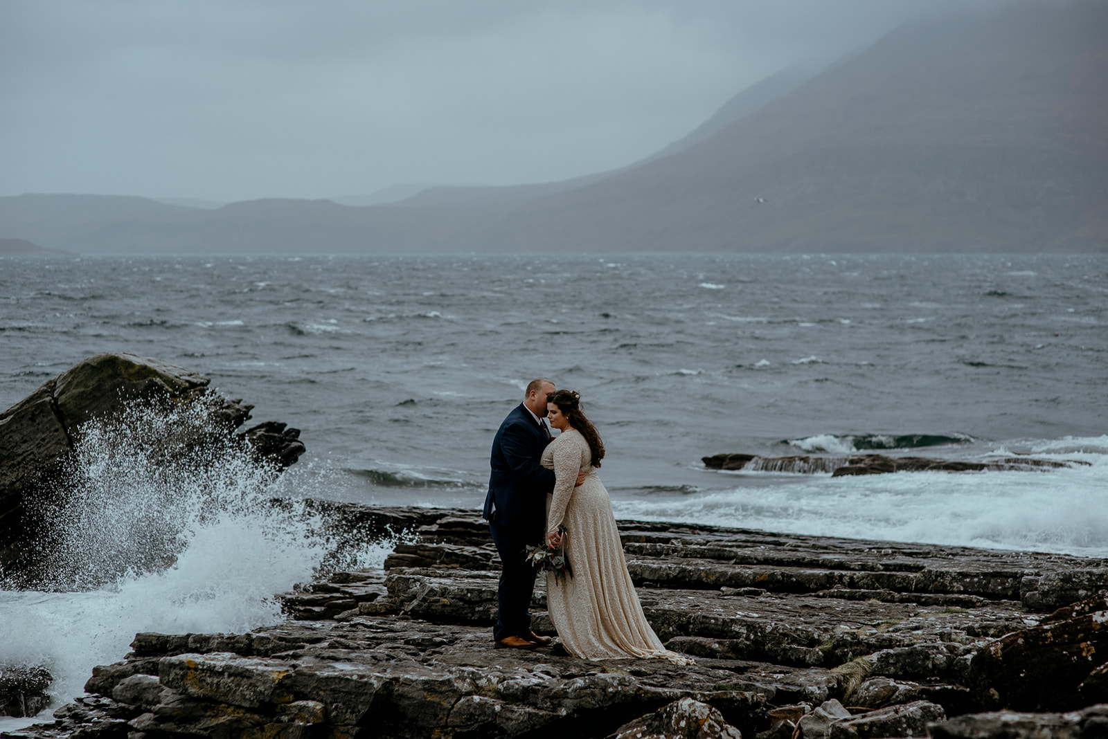 Couple kiss stormy seas on Isle of Skye
