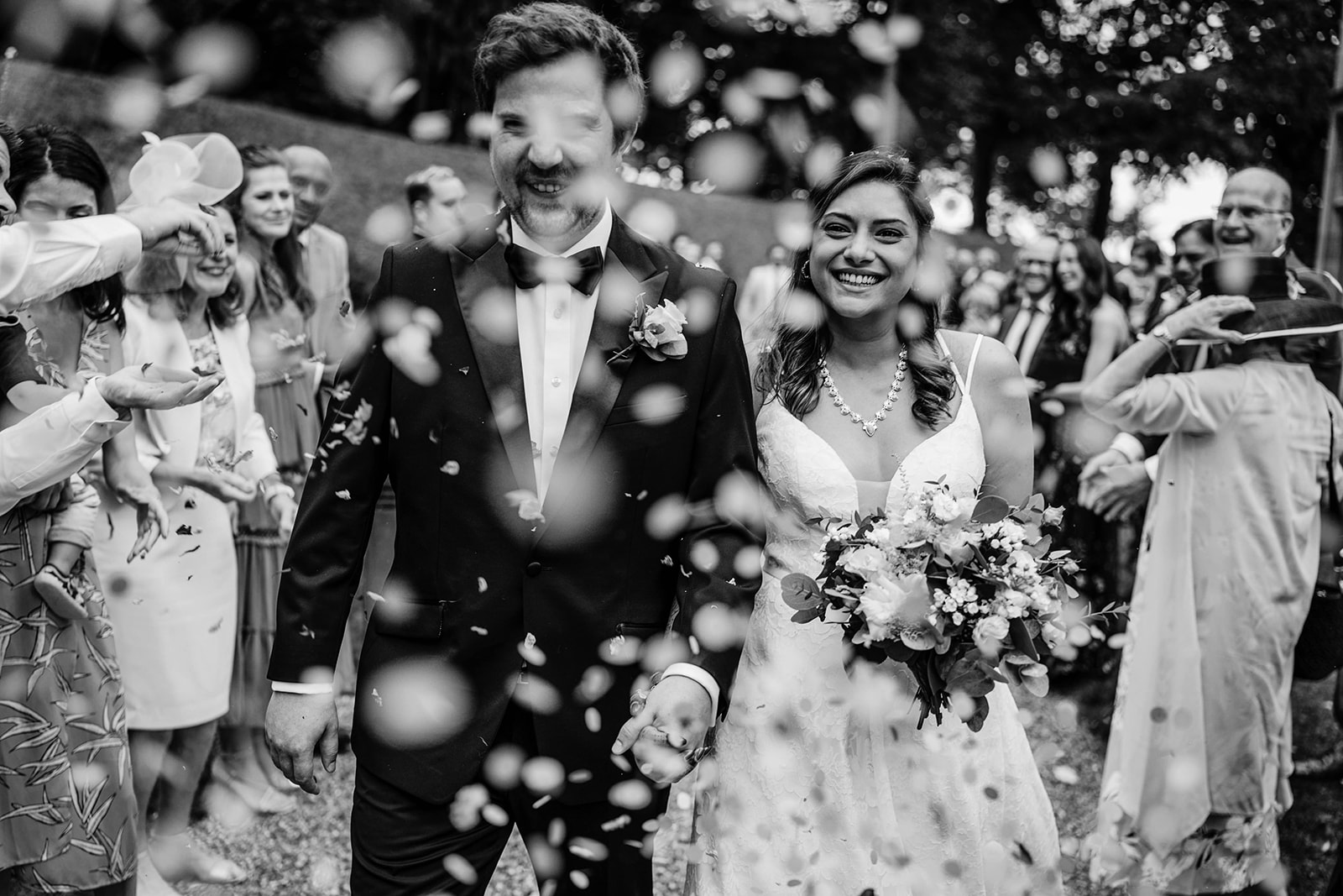 contemporary black and white picture of bride and groom having confetti thrown on them at Coombe Lodge blagdon