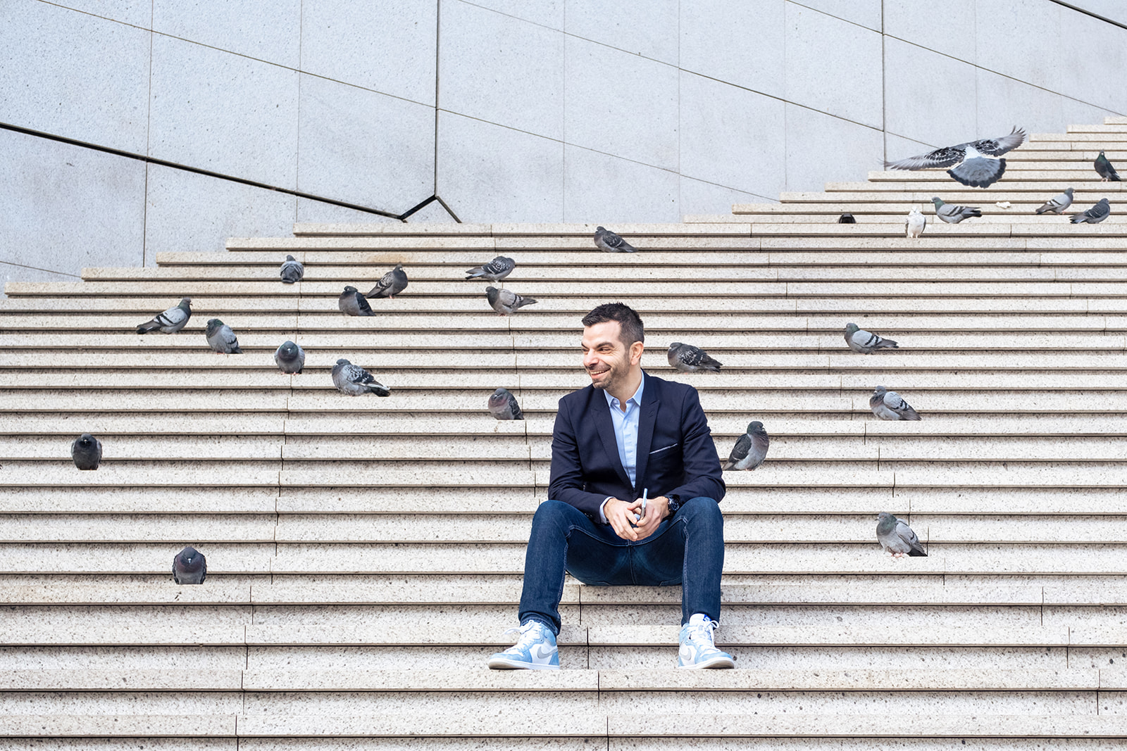 Portrait Jonathan Malka entouré de pigeons, marches de la Grande Arche de la Défense par Julien Pasternak photographe