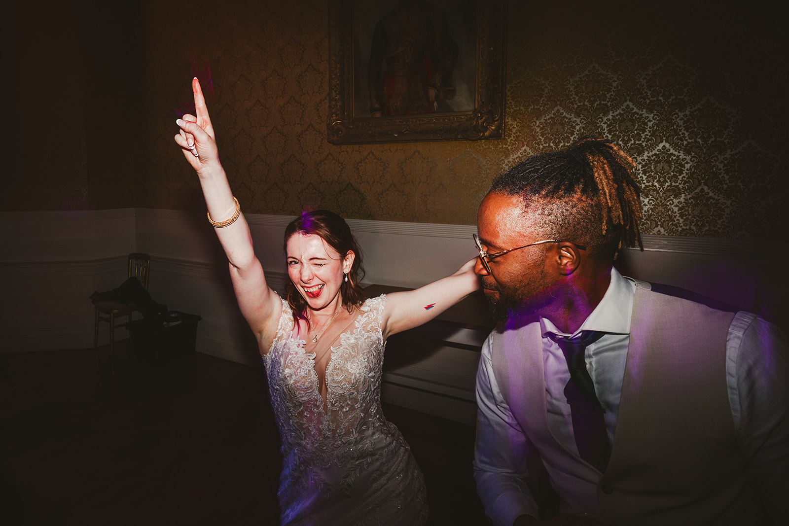 I bride winking into the camera whilst dancing at her wedding reception at Grittleton House