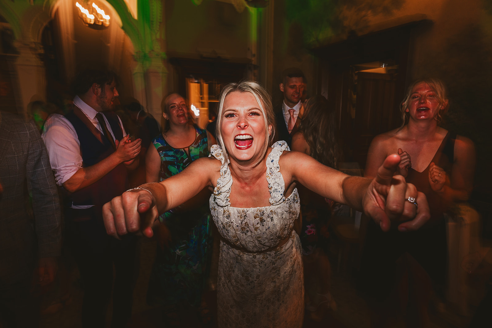 A female wedding guest pointing into the camera during the dancing reception at Clevedon Hall