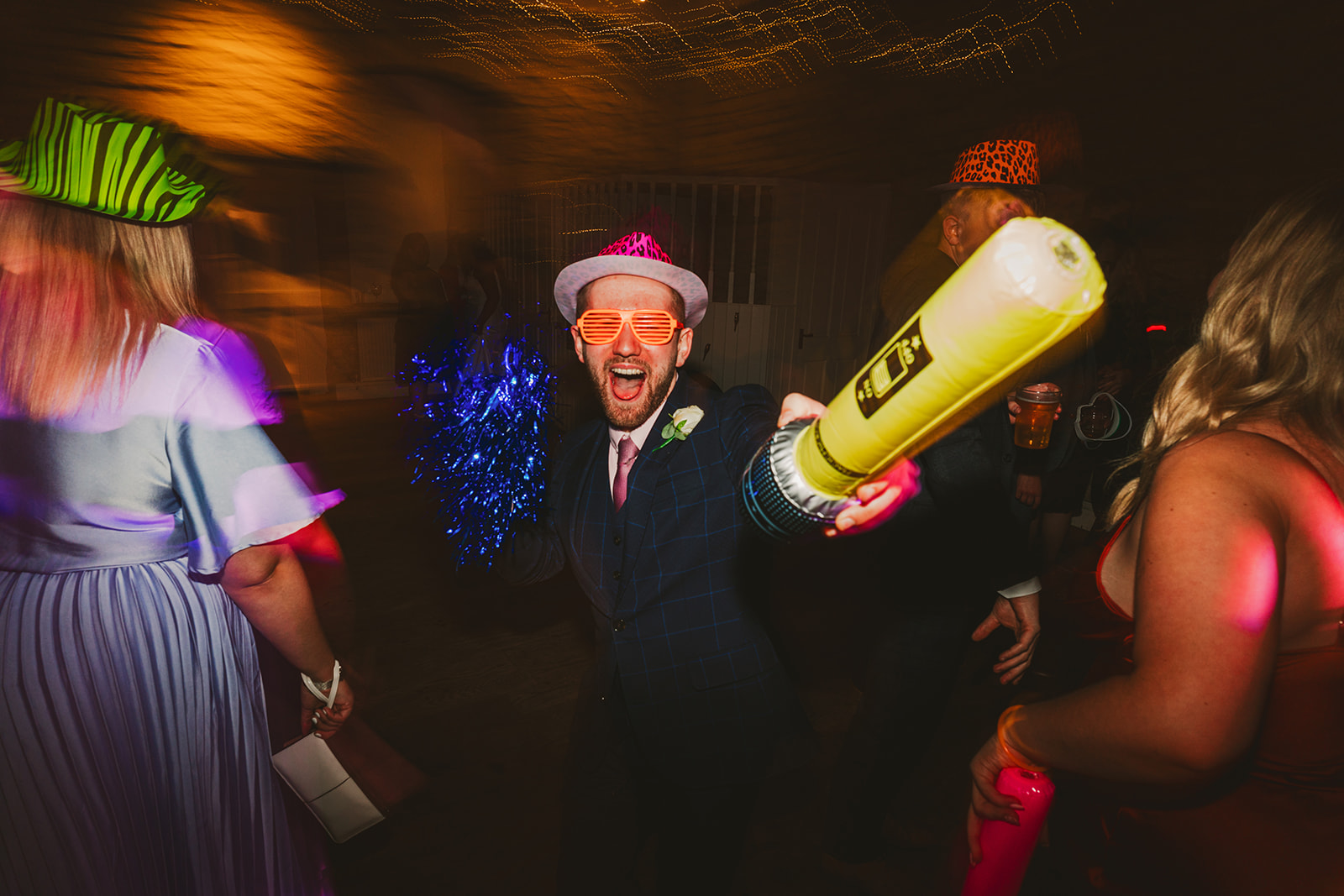 A wedding guest wearing sunglasses and holding a blow up mic on the dance floor at Brympton House