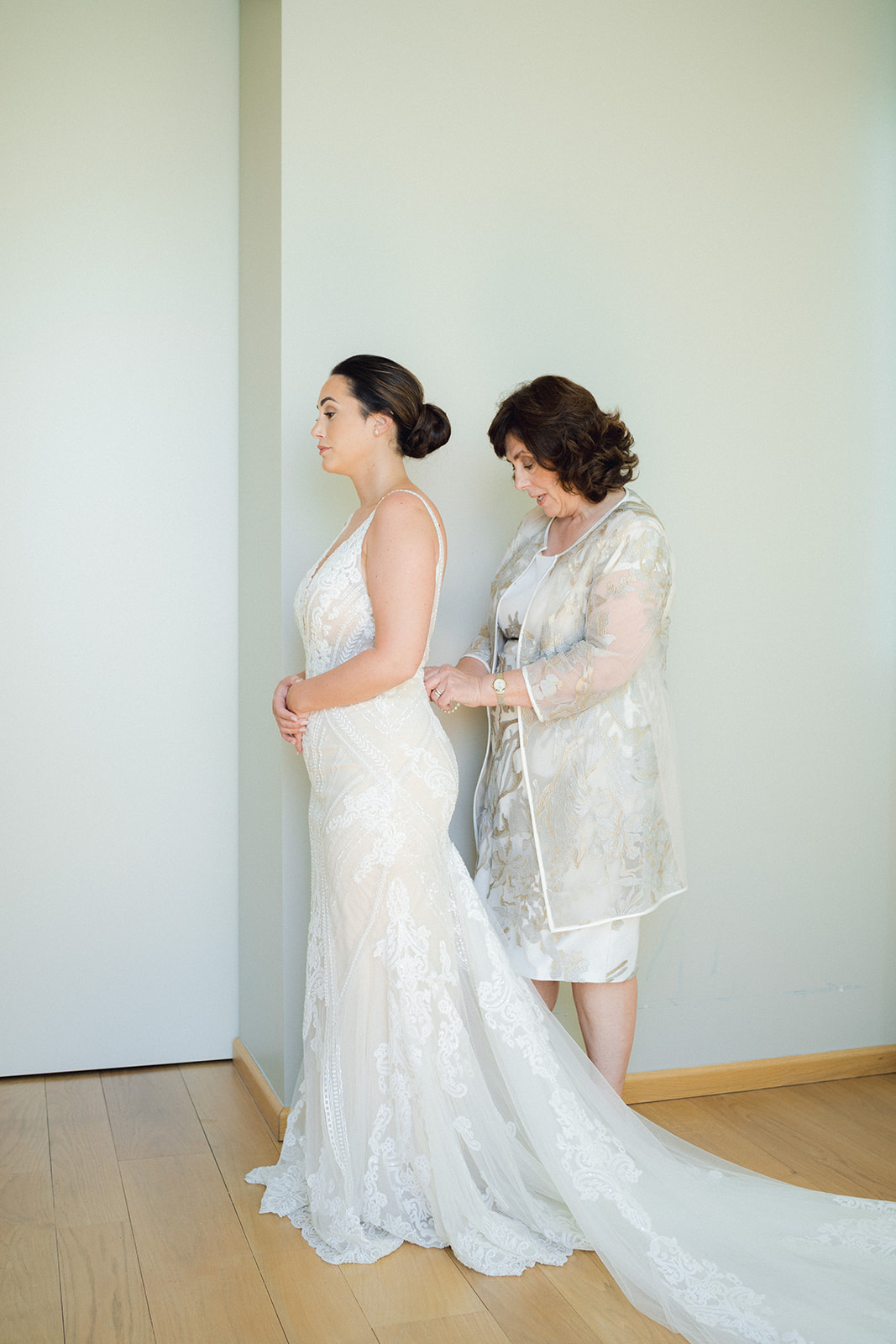 The mother of the bride helps the bride to fasten the dress