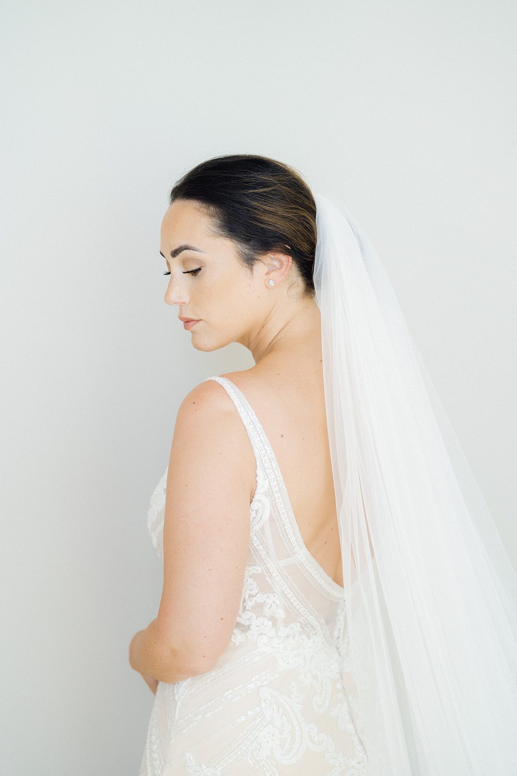 The bride, with an updo hairstyle, wears her white veil to match her white lace dress