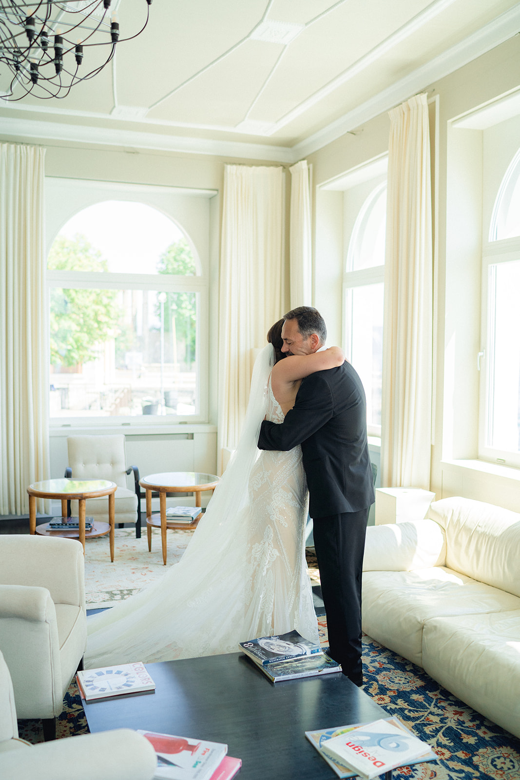 he bride embraces her father dressed in her wedding gown and veil in the lobby of Hotel Bellariva in Riva del Garda