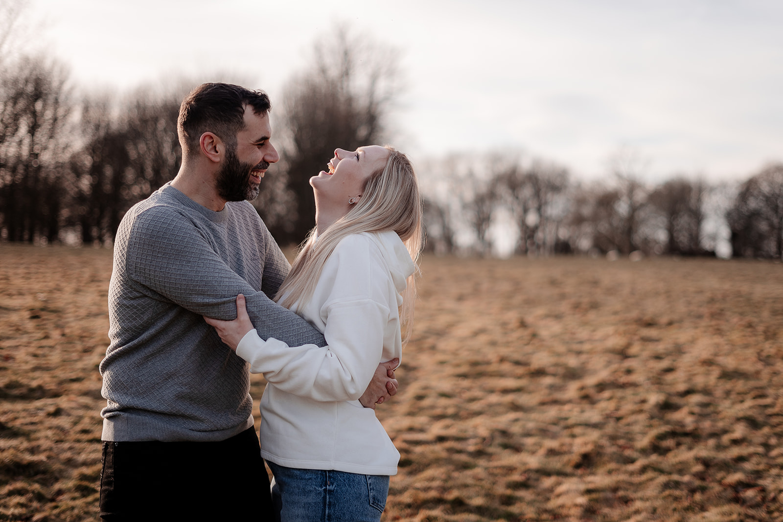 An engaged couple laugh together and hug on their pre-wedding photoshoot in Hampshire