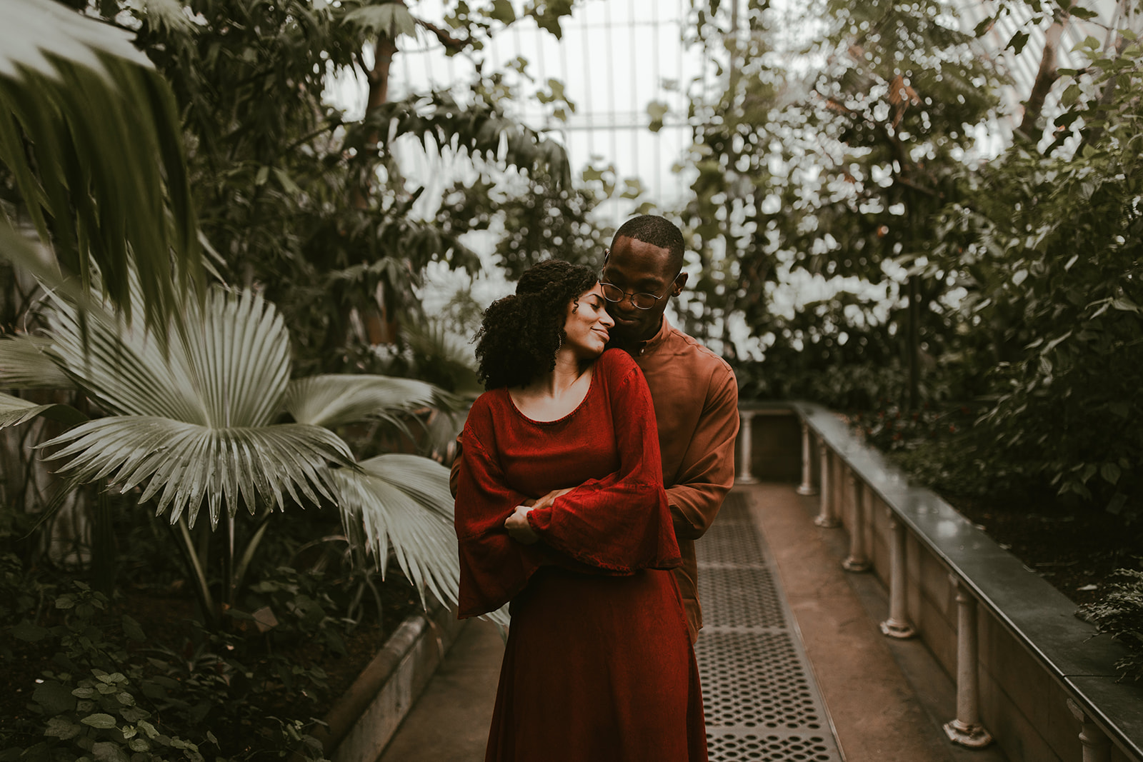couple embrace on their engagement shoot in a botanical greenhouse