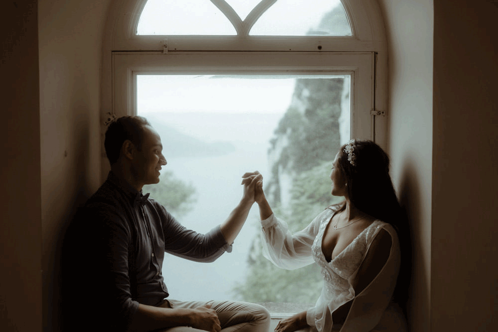 Ein Paar, das ihr Hände berührt vor einem Fenster der Villa Lysis auf der Insel Capri in Italien
