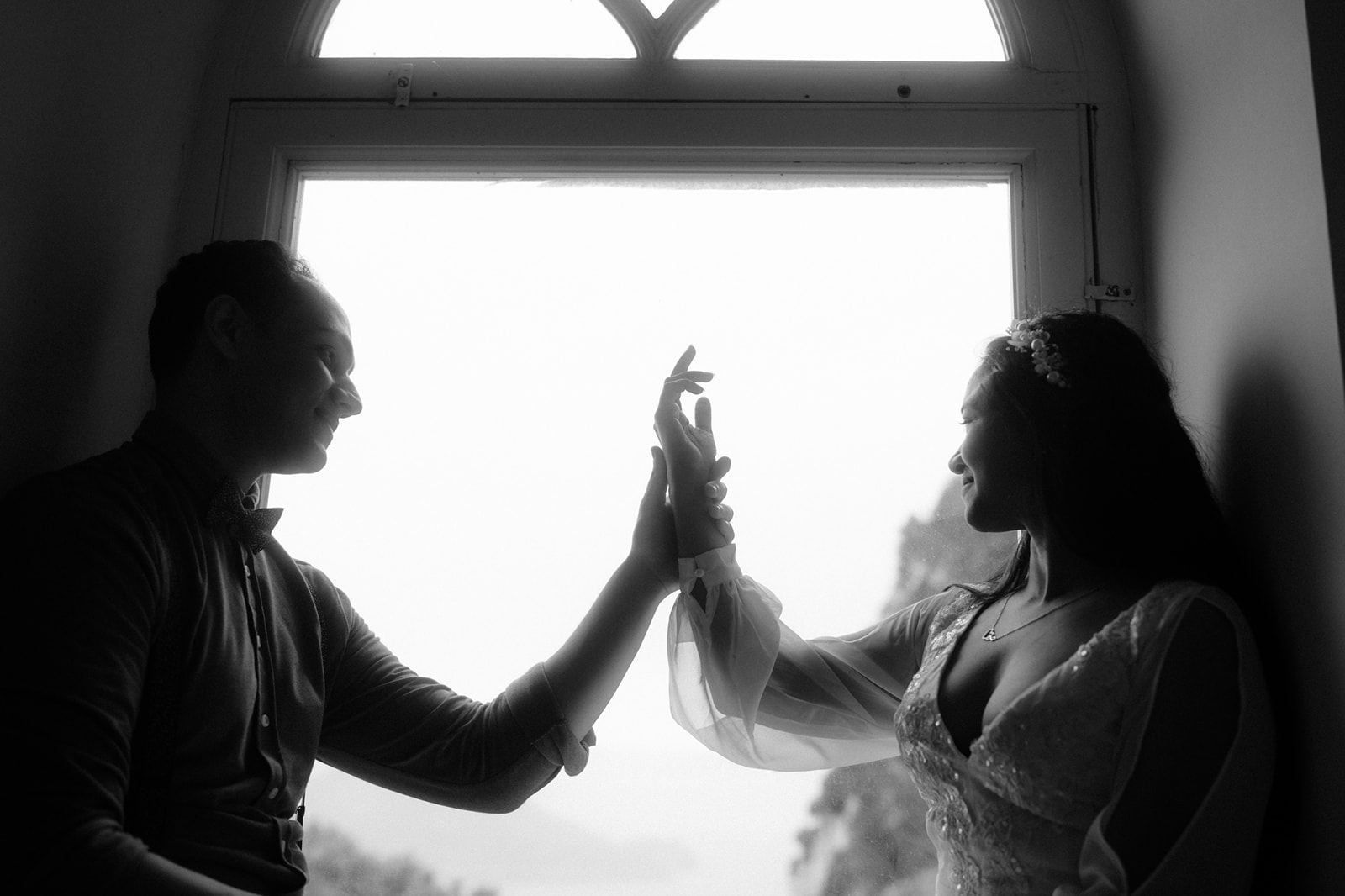 A couple touching their hands in front of a window of Villa Lysis on the island of Capri in Italy