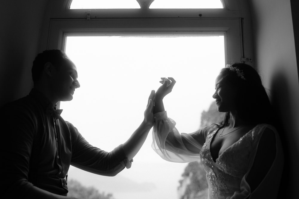A couple touching their hands in front of a window of Villa Lysis on the island of Capri in Italy