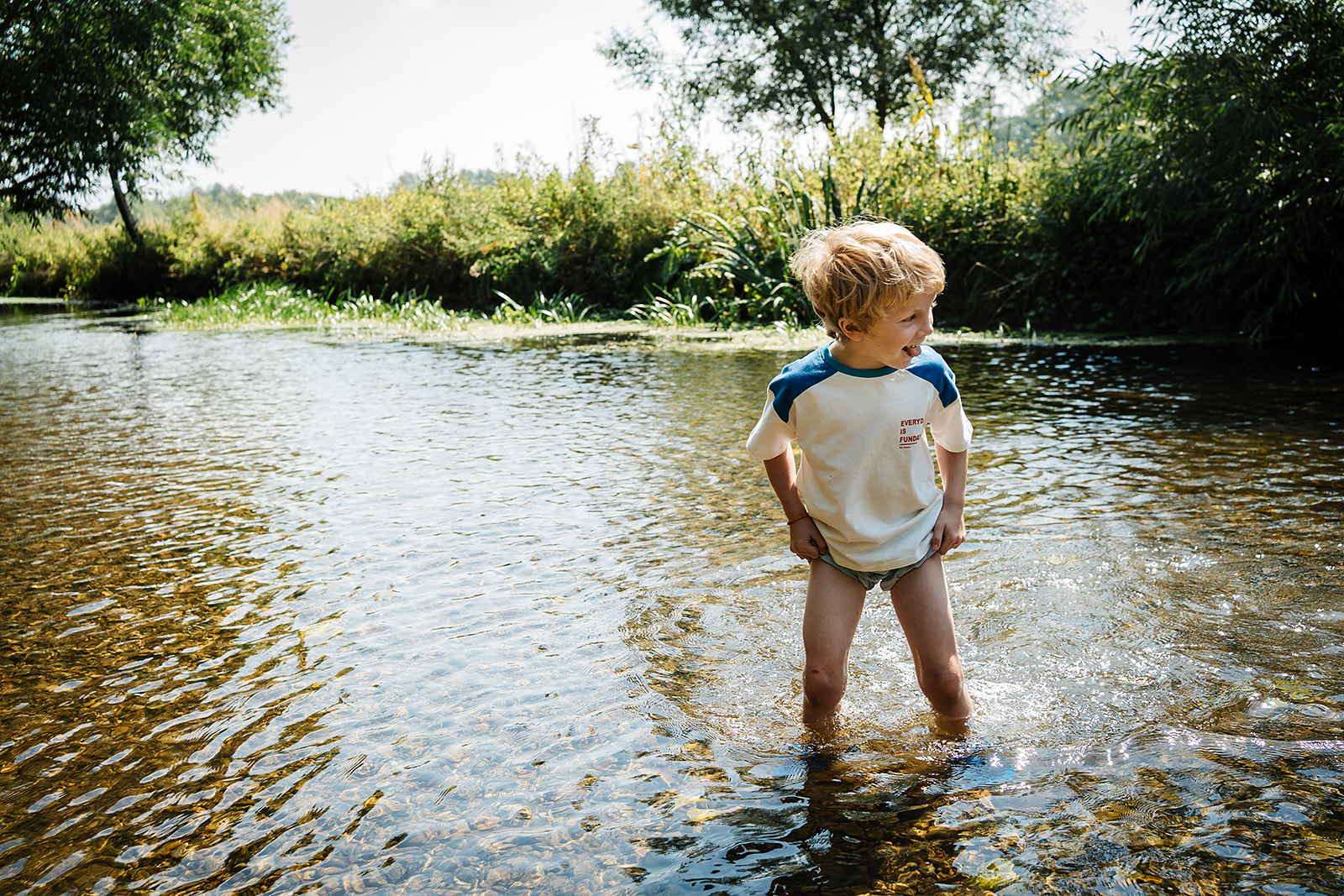 Boy padding in the river on the edge of Norwich on a sunny day