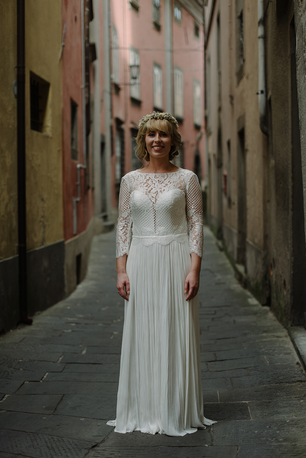 bride wears a beautiful boho style dress and is standing in the quiet streets of the old town of barga