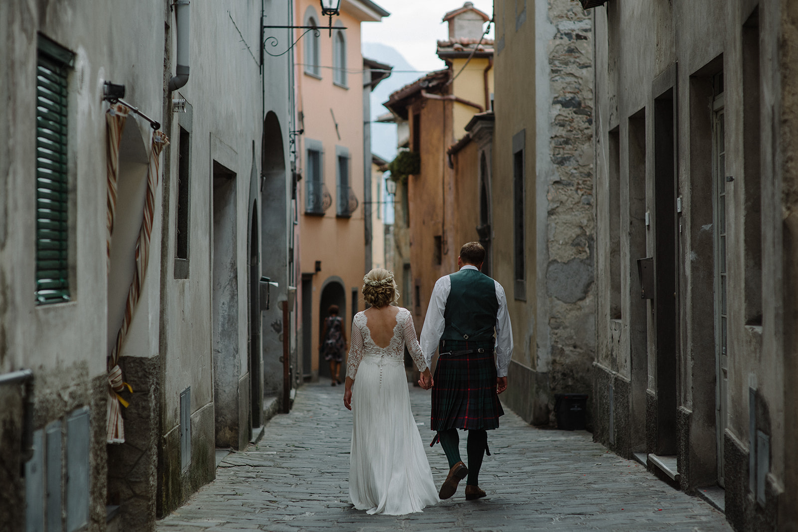 bride and groom walk through the old town of Barga holding hands