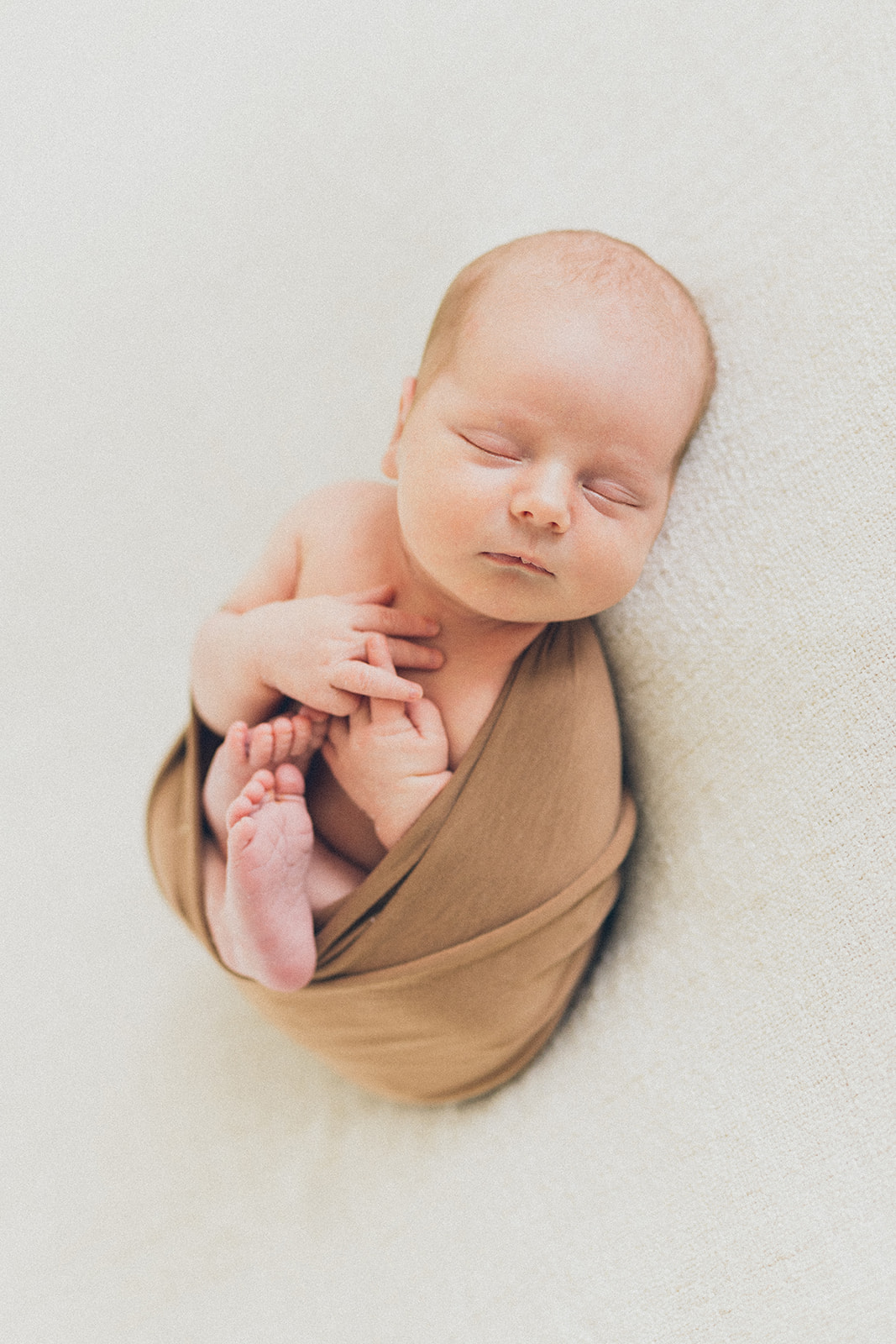 Beautiful newborn baby boy wrapped in a simple tan wrap at RinkaDink Studio Belfast
