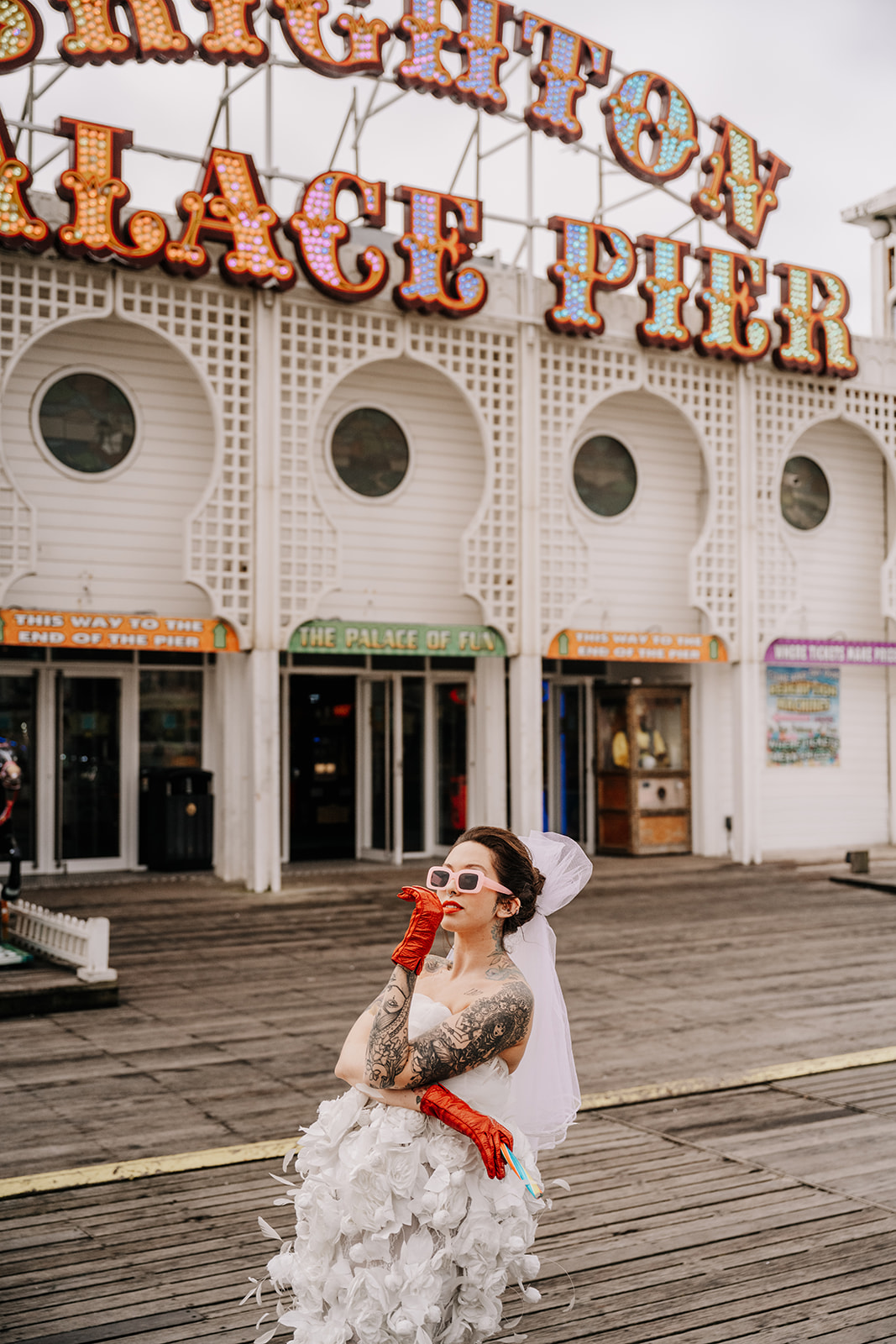 A tattoed bride in a wedding dress, In front of the Birght Palace Pier sign