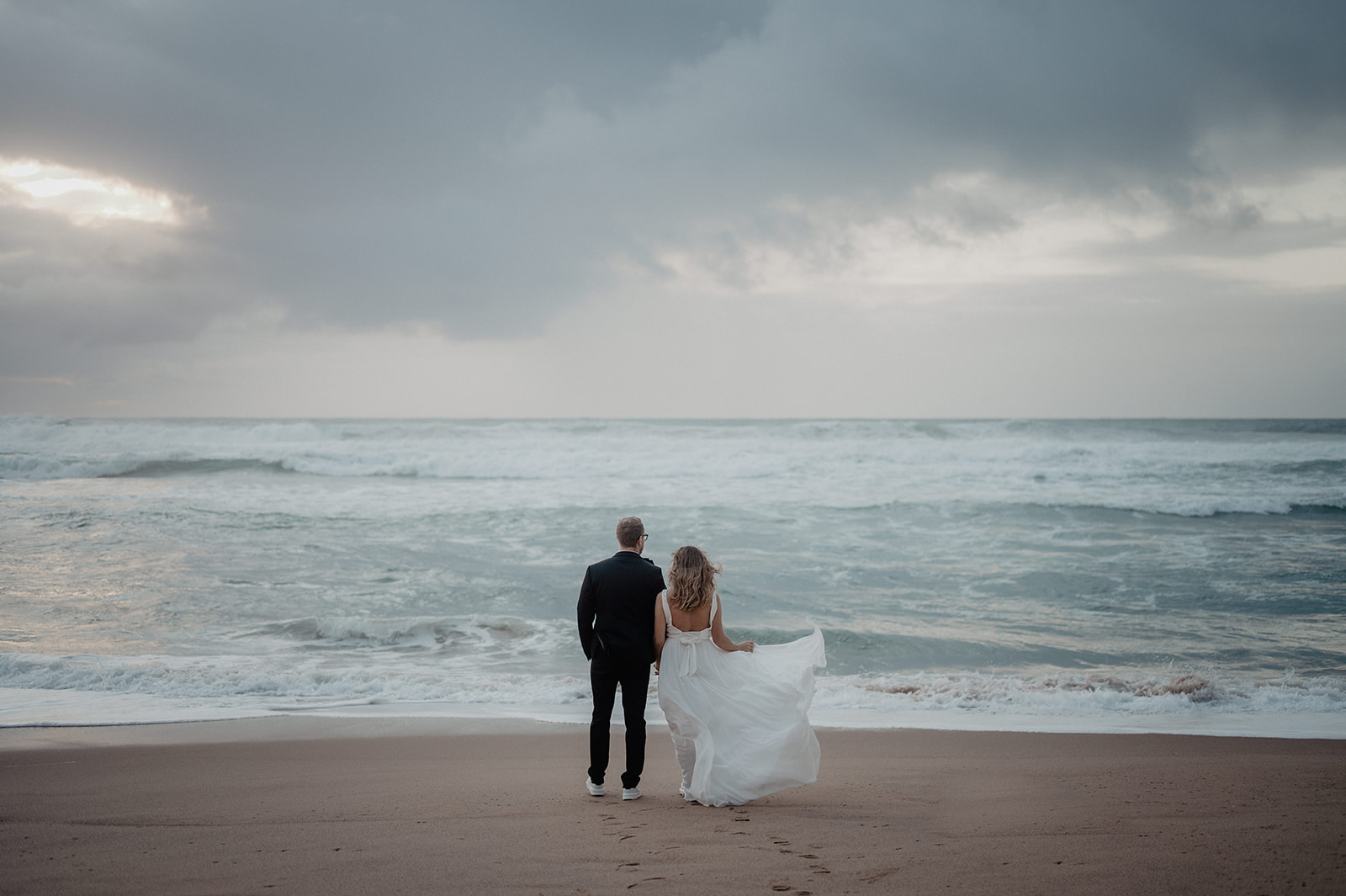 Brautpaar spaziert am Strand von Portugal
