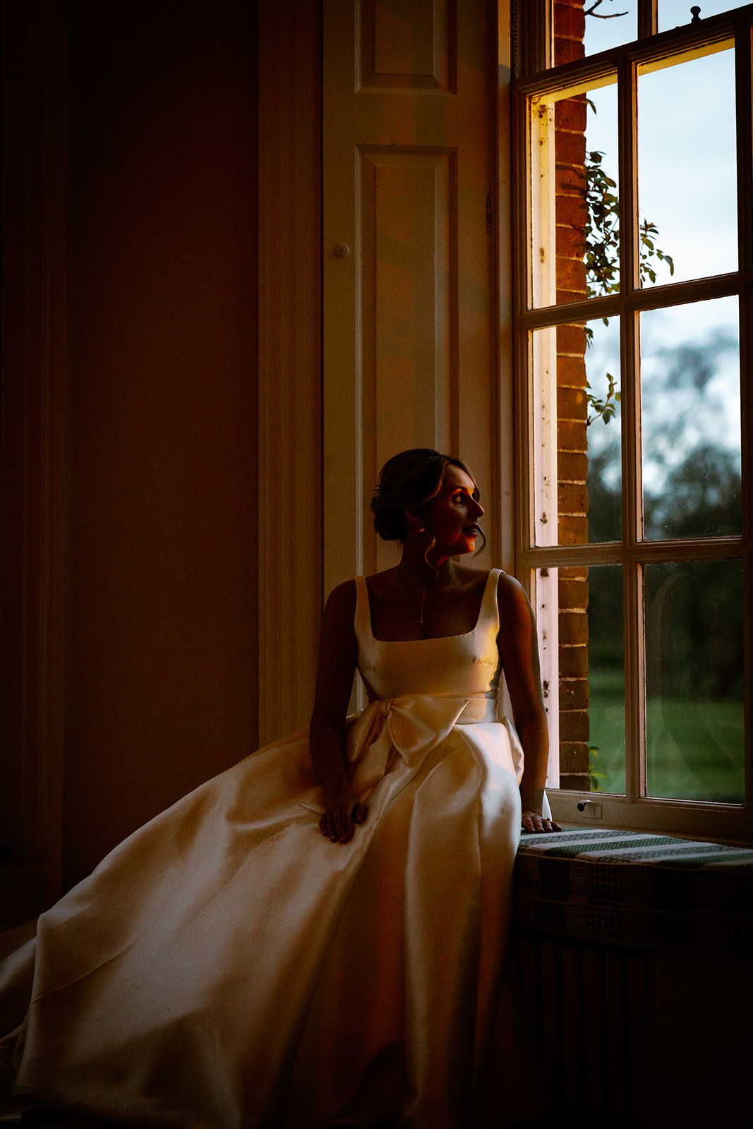 bride looking out the window at sunset at iscoyd park