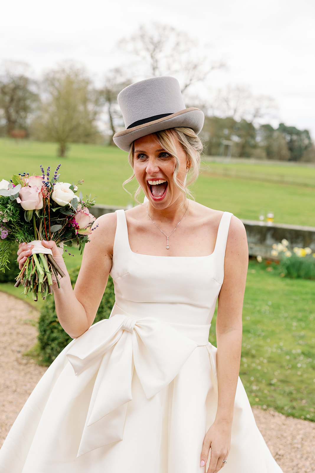 a silly wedding photo of a bride wearing the grooms top hat