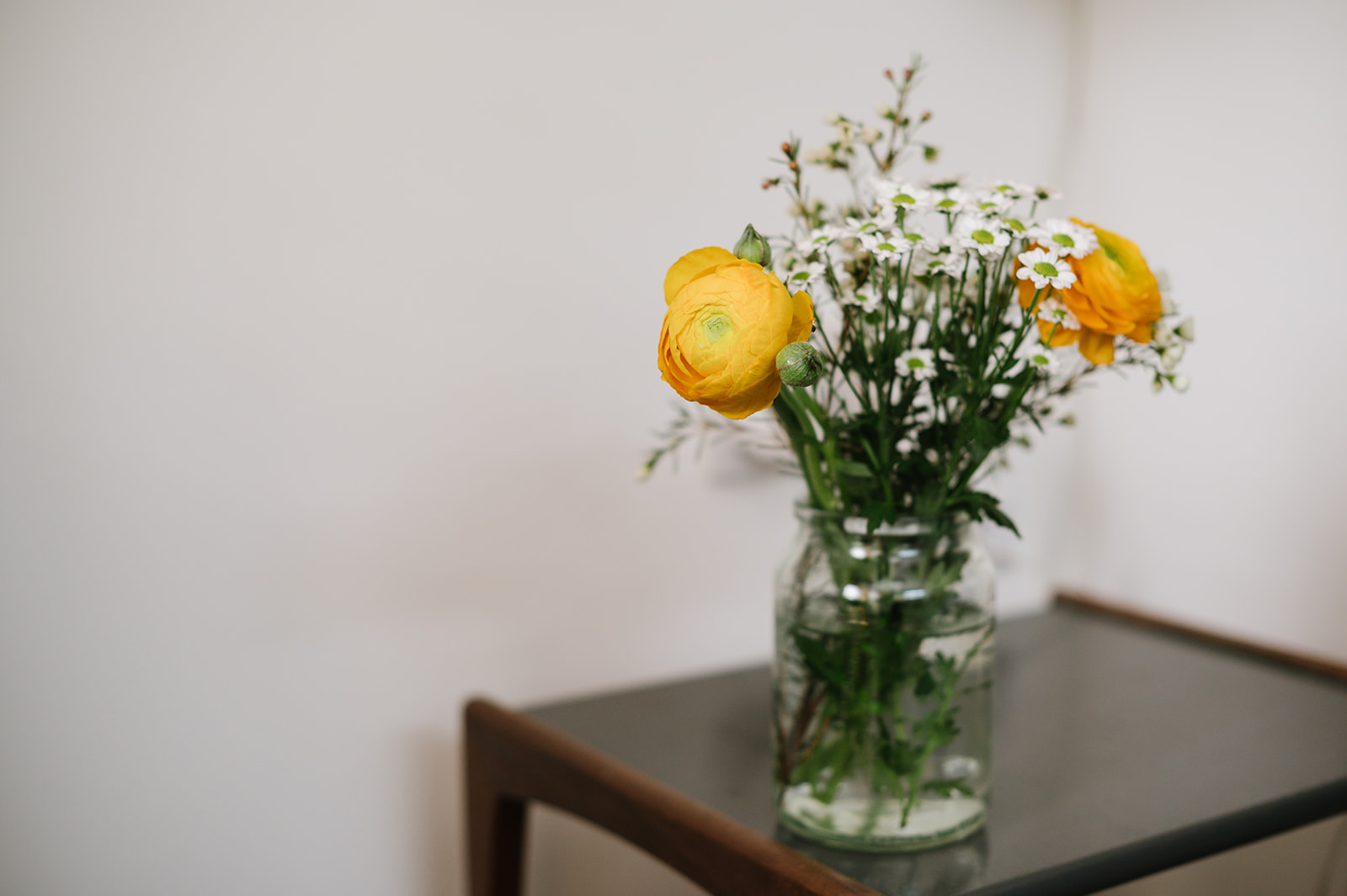 a flower arrangement with yellow and white flowers in a jar