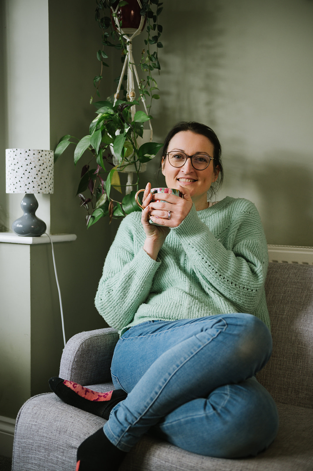 smiling woman drinking tea sitting on the sofa for her business headshots