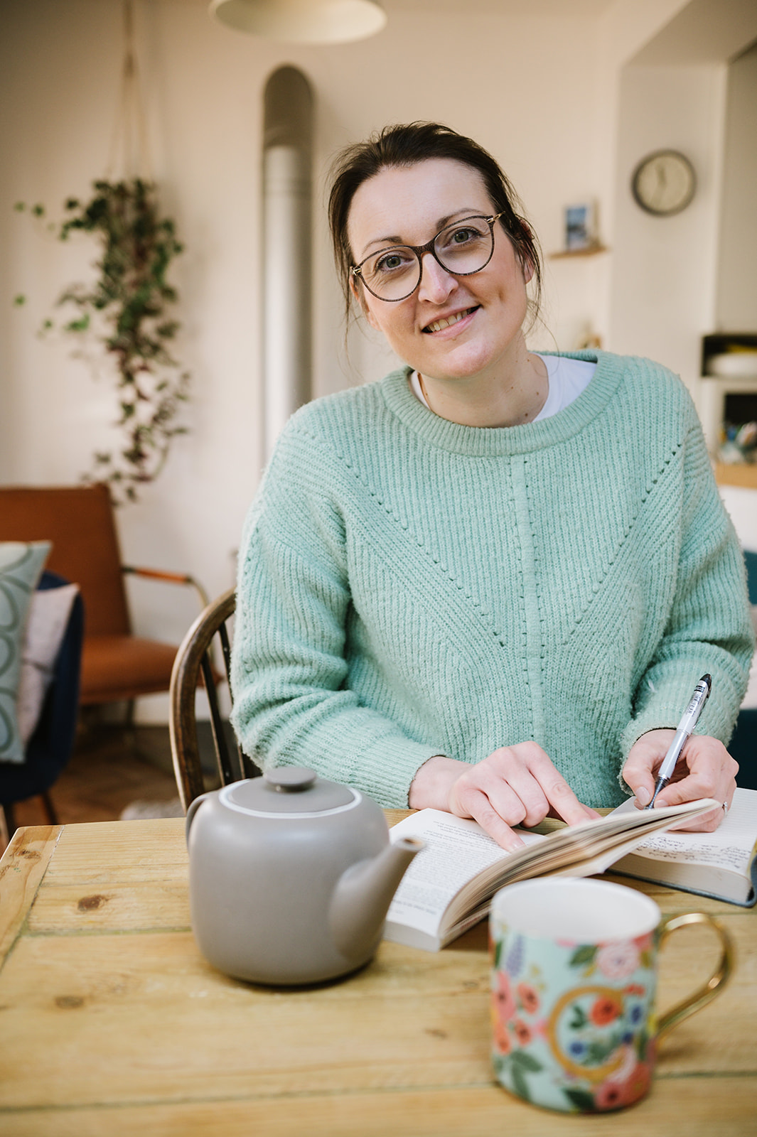 woman smiling looking at the camera with a book and a tea pot for her business headshots