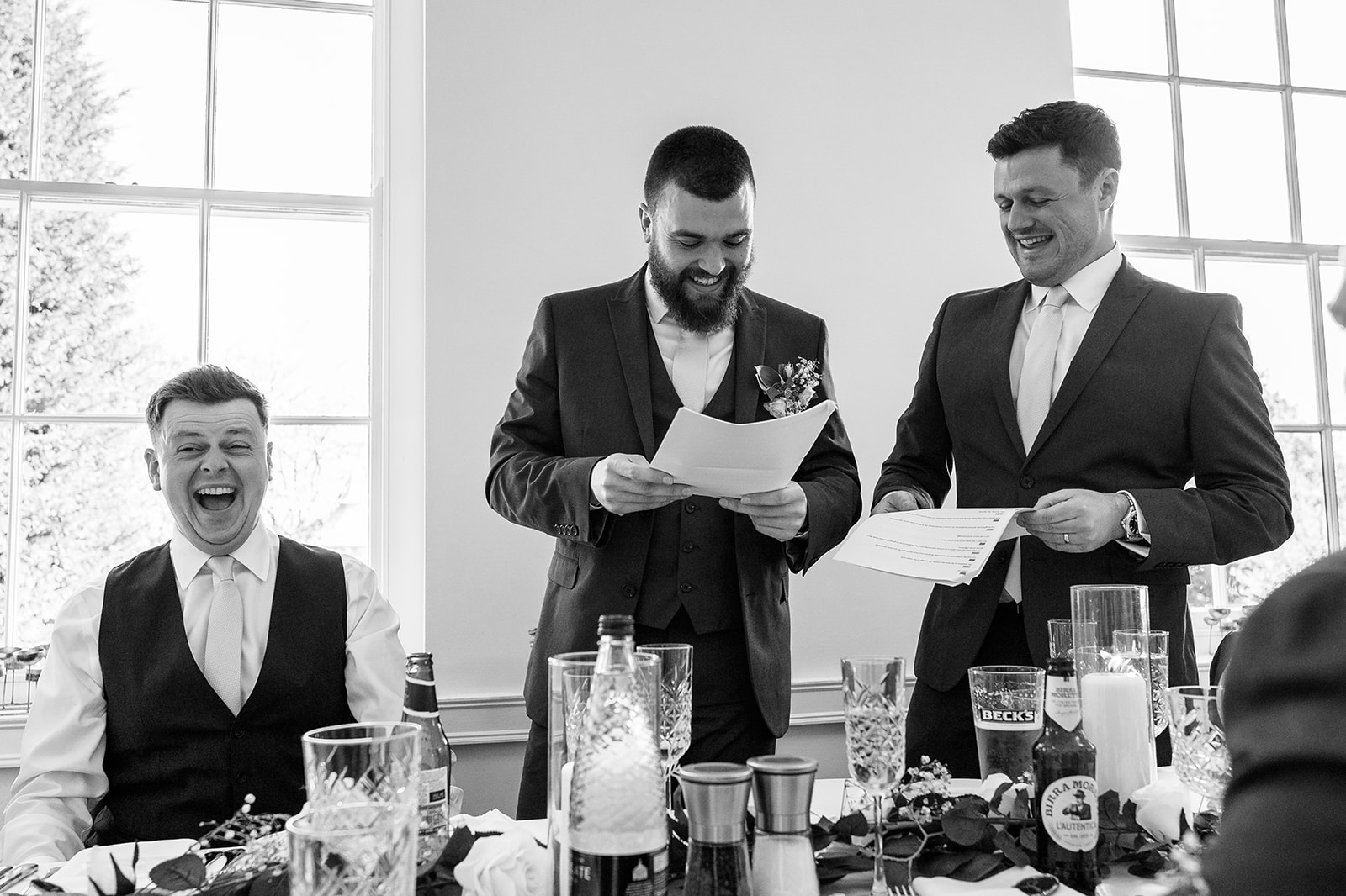 The groom, laughing at his best men's wedding speech 