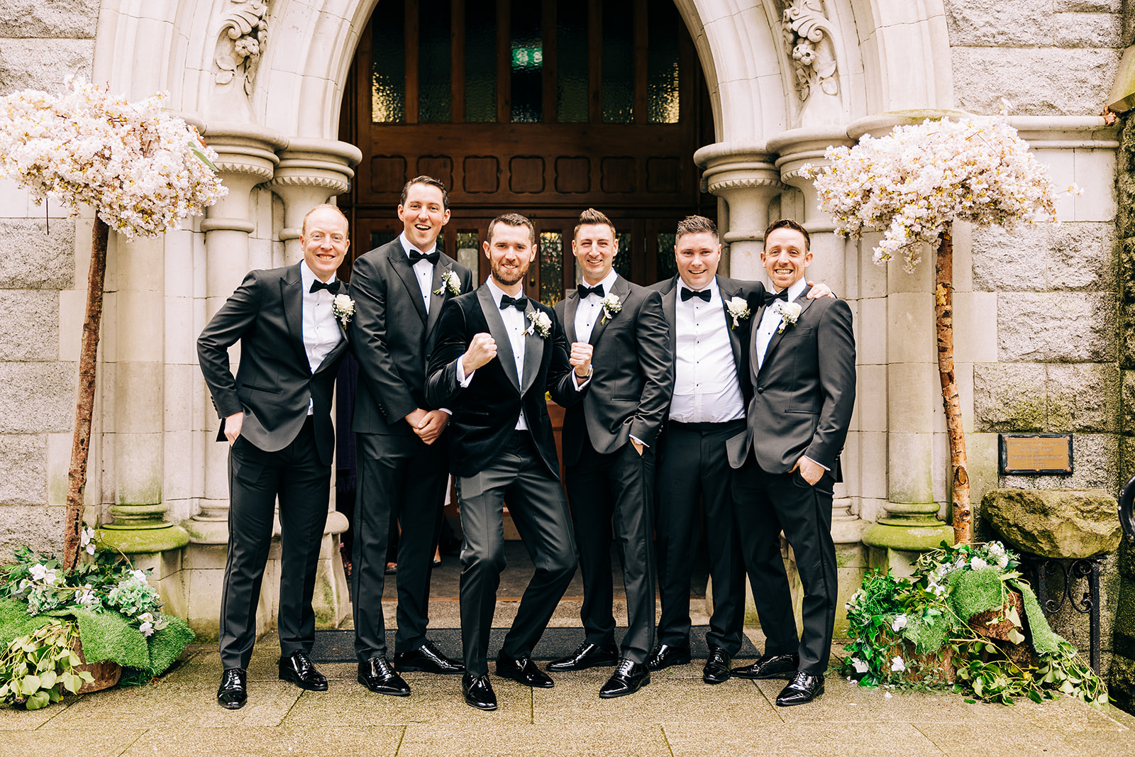 a groom and his grooms men pose for photos outside the Church of the Annunciation Grange Rd