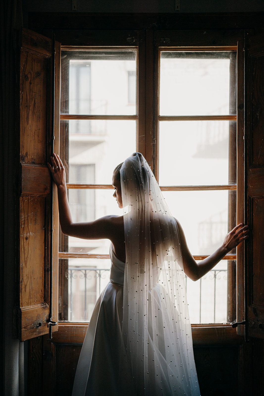 Moody, editorial styled image showing bride looking out of the window