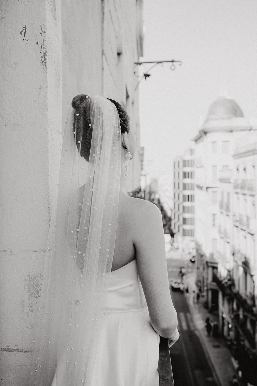 Black and white image of bride looking out on the balcony
