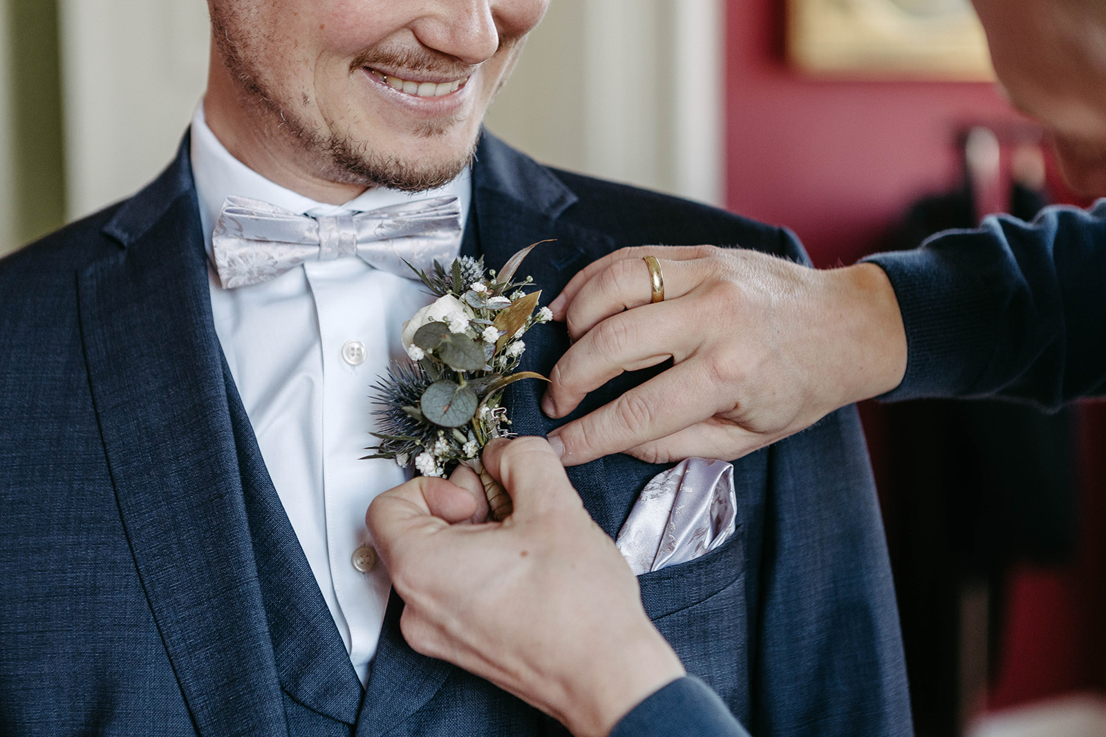 Nahaufnahme des eleganten Blumenansteckers, der am Revers des Bräutigams für die Hochzeit im Schloss Jägersburg