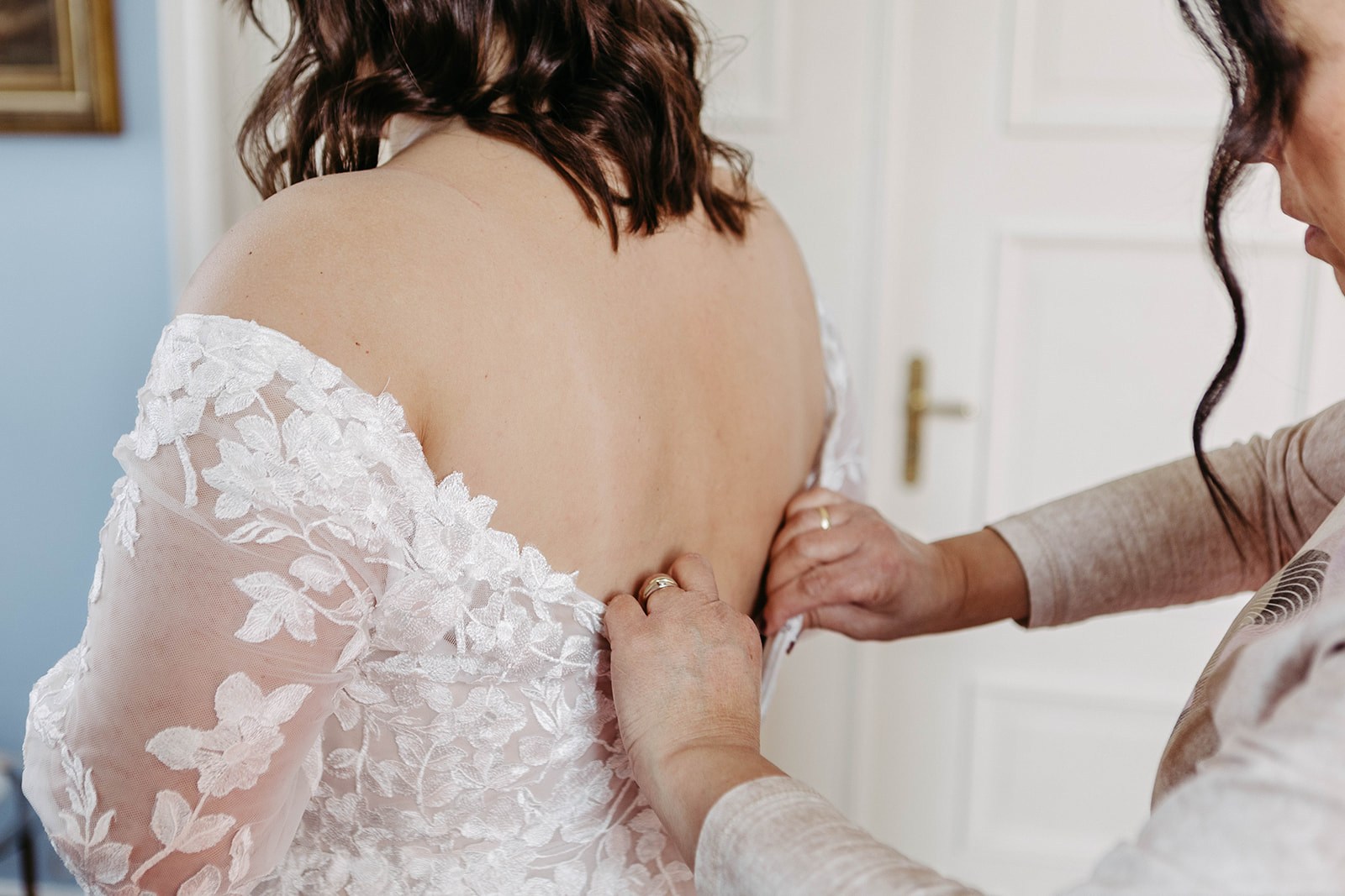 Brautmutter schließt das Kleid – detailverliebte Aufnahme vor der Hochzeit im Schloss Jägersburg