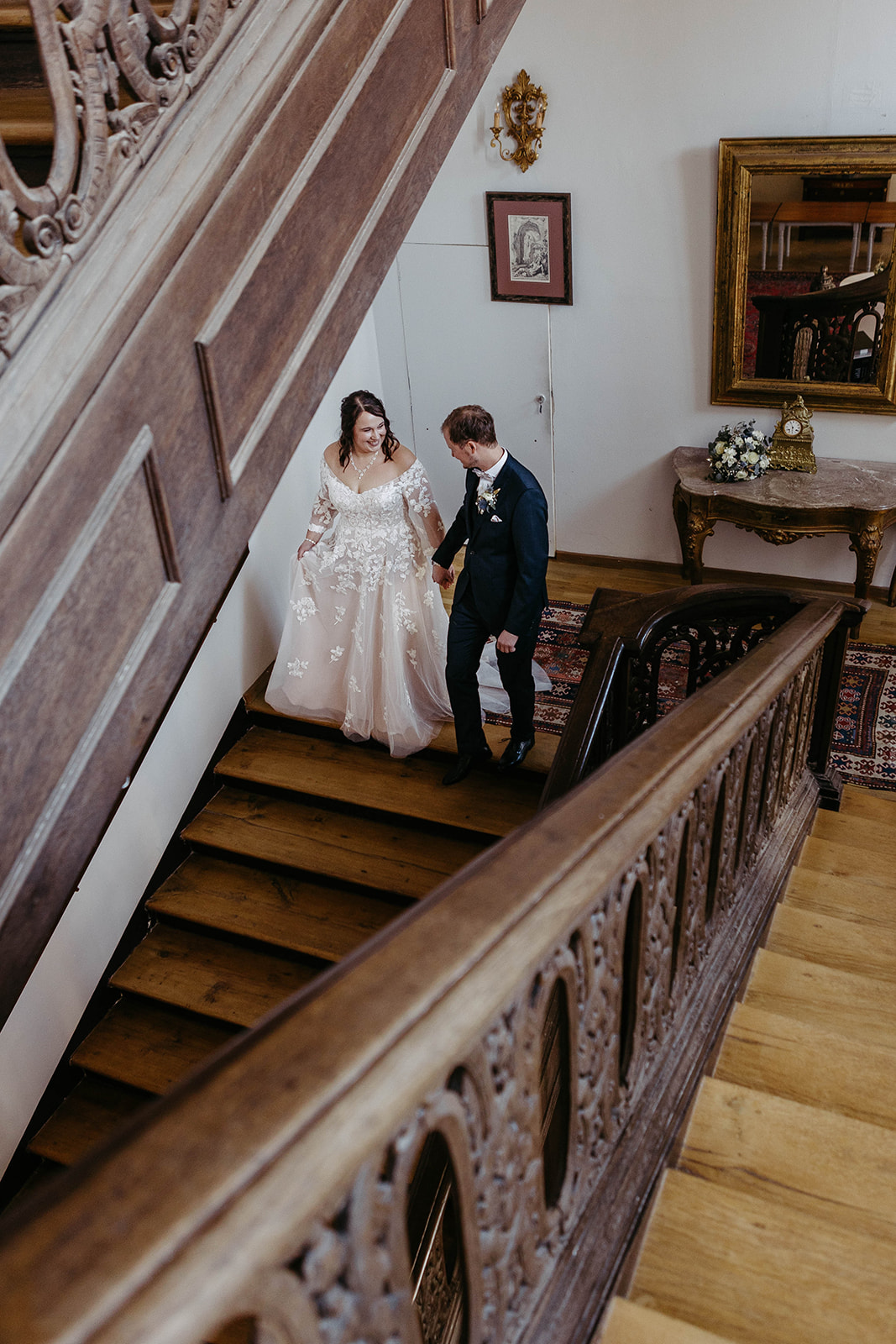 Eleganter Moment: Das Hochzeitspaar schreitet vorwärts die imposante Treppe des Schlosses Jägersburg hinunter