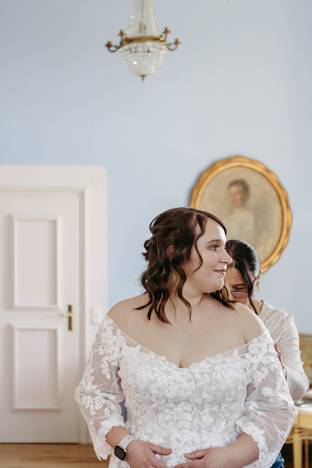 Brautmutter schließt Kleid, Braut blickt träumerisch aus dem Fenster – emotionale Szene im Schloss Jägersburg