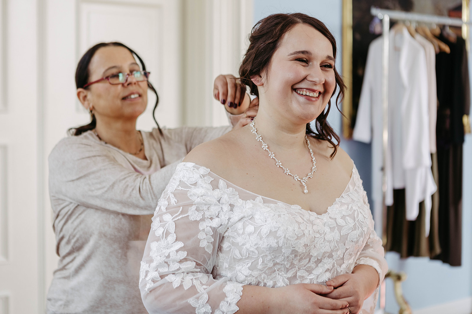 Braut lacht, Kleid wird geschlossen – freudiger Augenblick vor der Hochzeit im Schloss Jägersburg