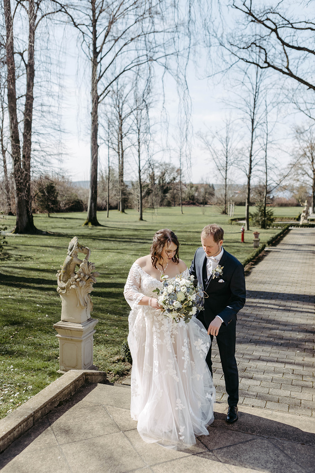 Natürliche Schönheit: Das Hochzeitspaar spaziert durch den malerischen Schlossgarten, im Hintergrund blüht der idyllisch