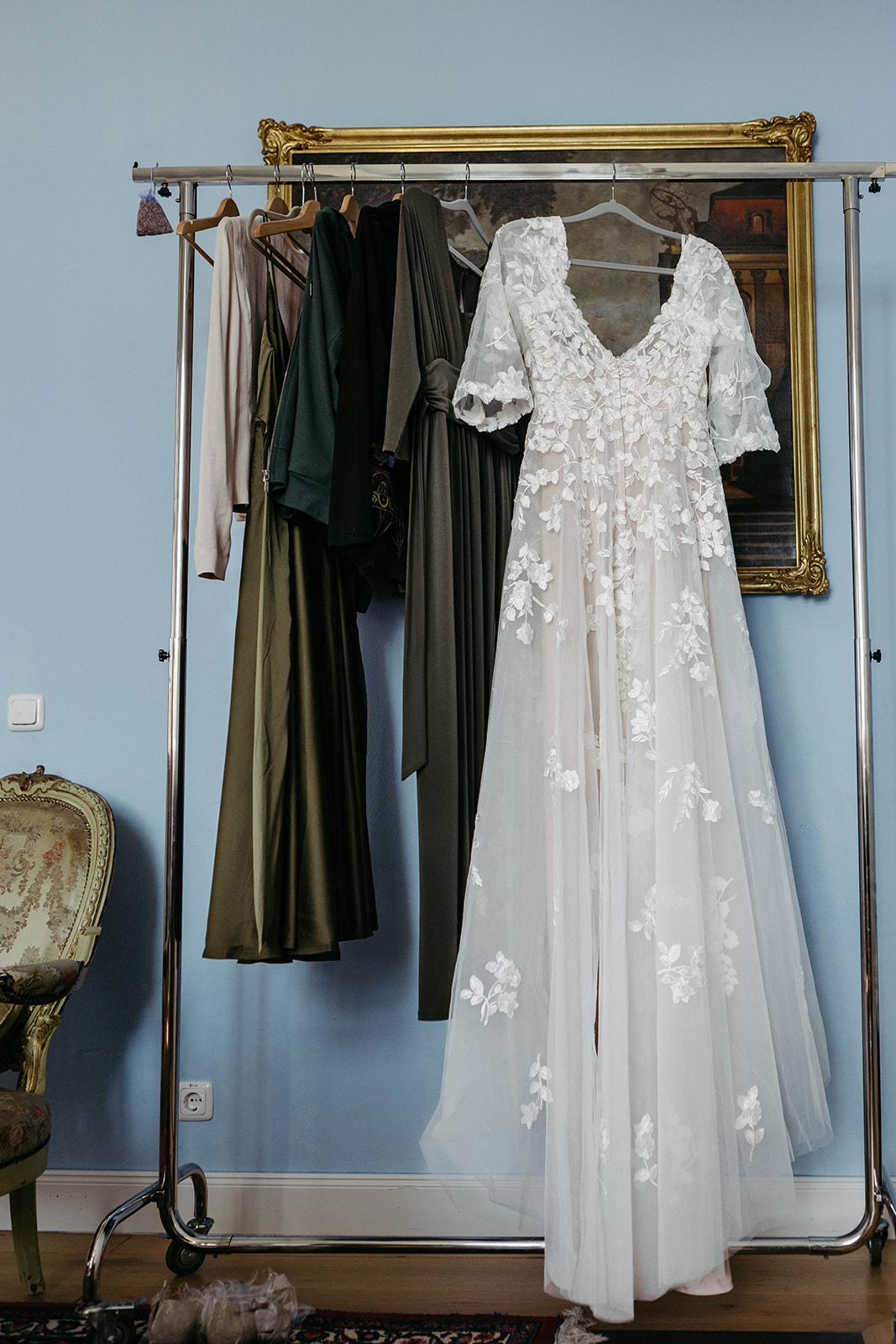 Bild zeigt das traumhafte Hochzeitskleid auf einer Kleiderstange vor einem historischen Gemälde im Schloss Jägersburg.
