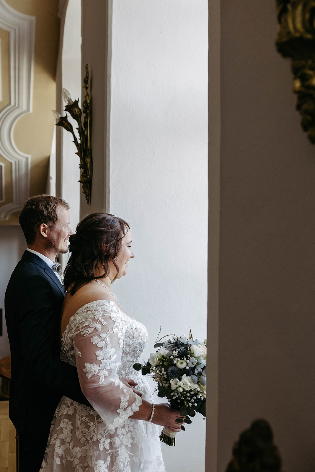Romantisches Szenario: Der Bräutigam steht zärtlich hinter der Braut, beide genießen den Ausblick aus dem Fenster des Sc