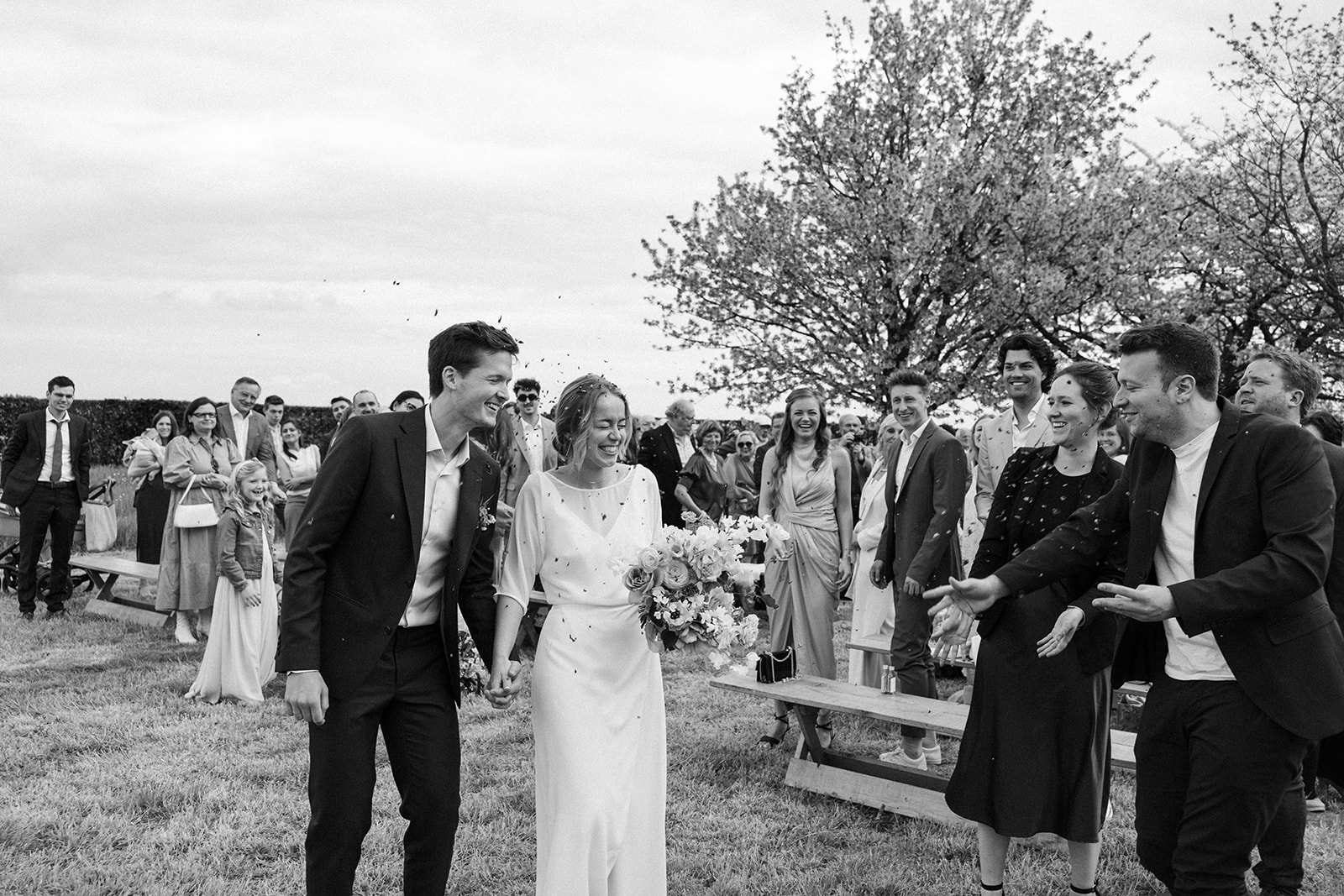 Couple's joyful exit as newlyweds, surrounded by family and friends