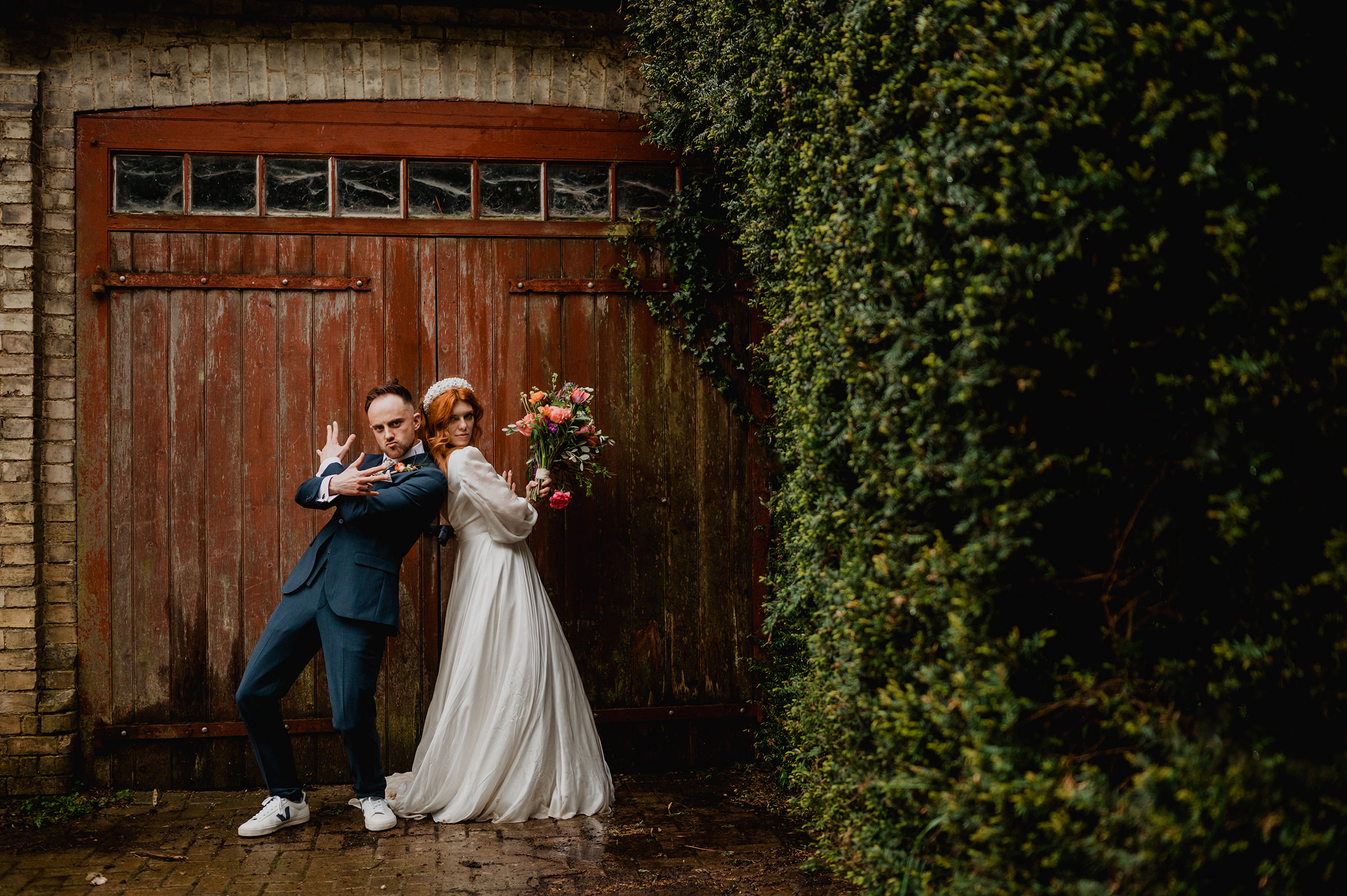 A couple strike a pose in front of a red door at South Farm wedding venue