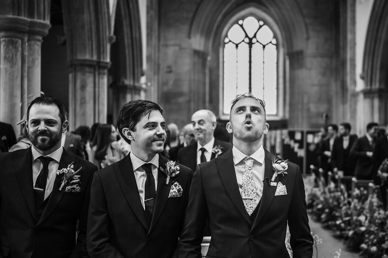 A nervous groom waits for his bride at the end of the aisle